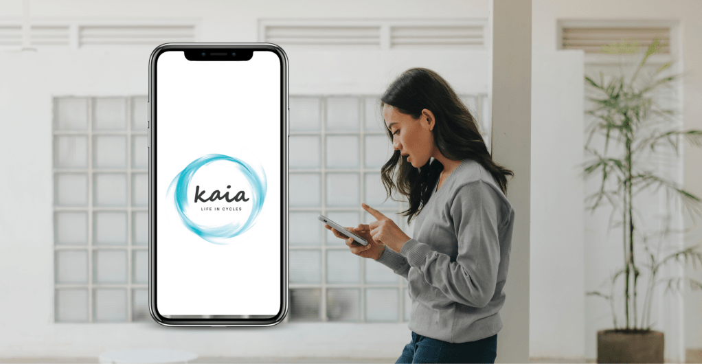 A picture of a girl looking at her phone with a wondrous expression. A mockup of the mobile phone with the logo of the app Kaia.